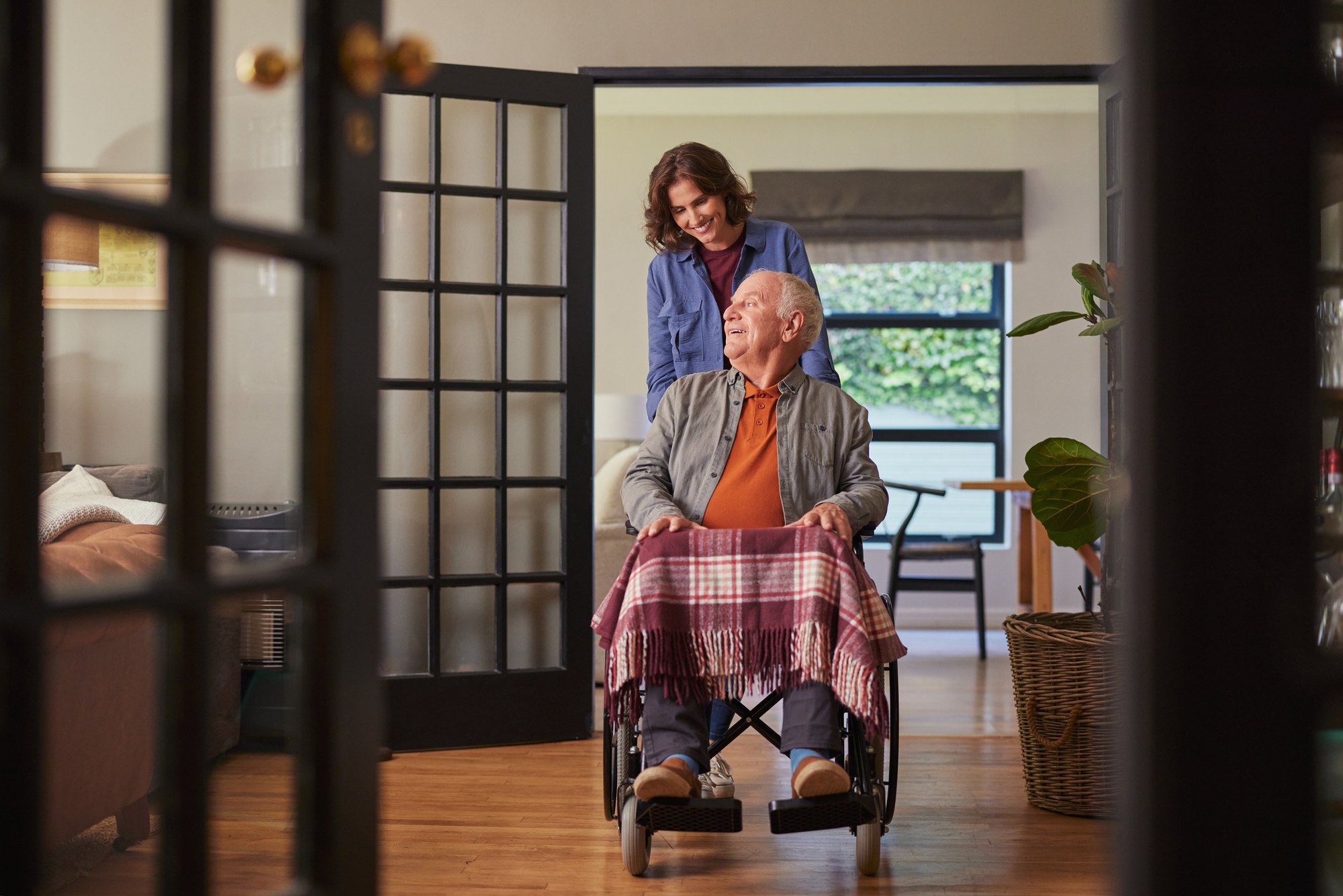 An older adult practices a hip strengthening exercise with a physical therapist at home