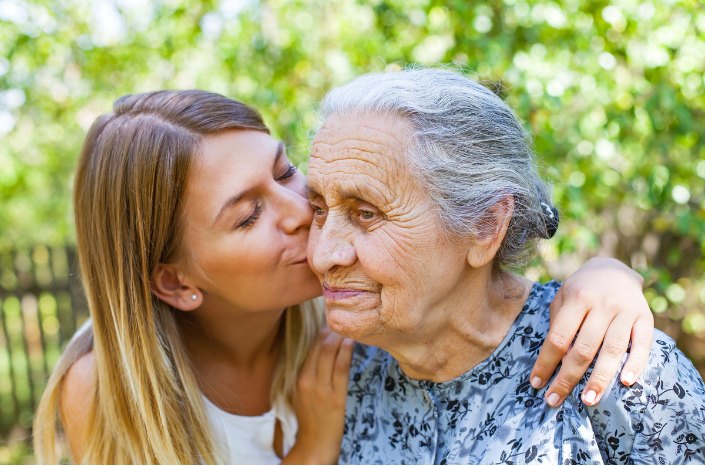 A daughter kisses her mother on the cheek