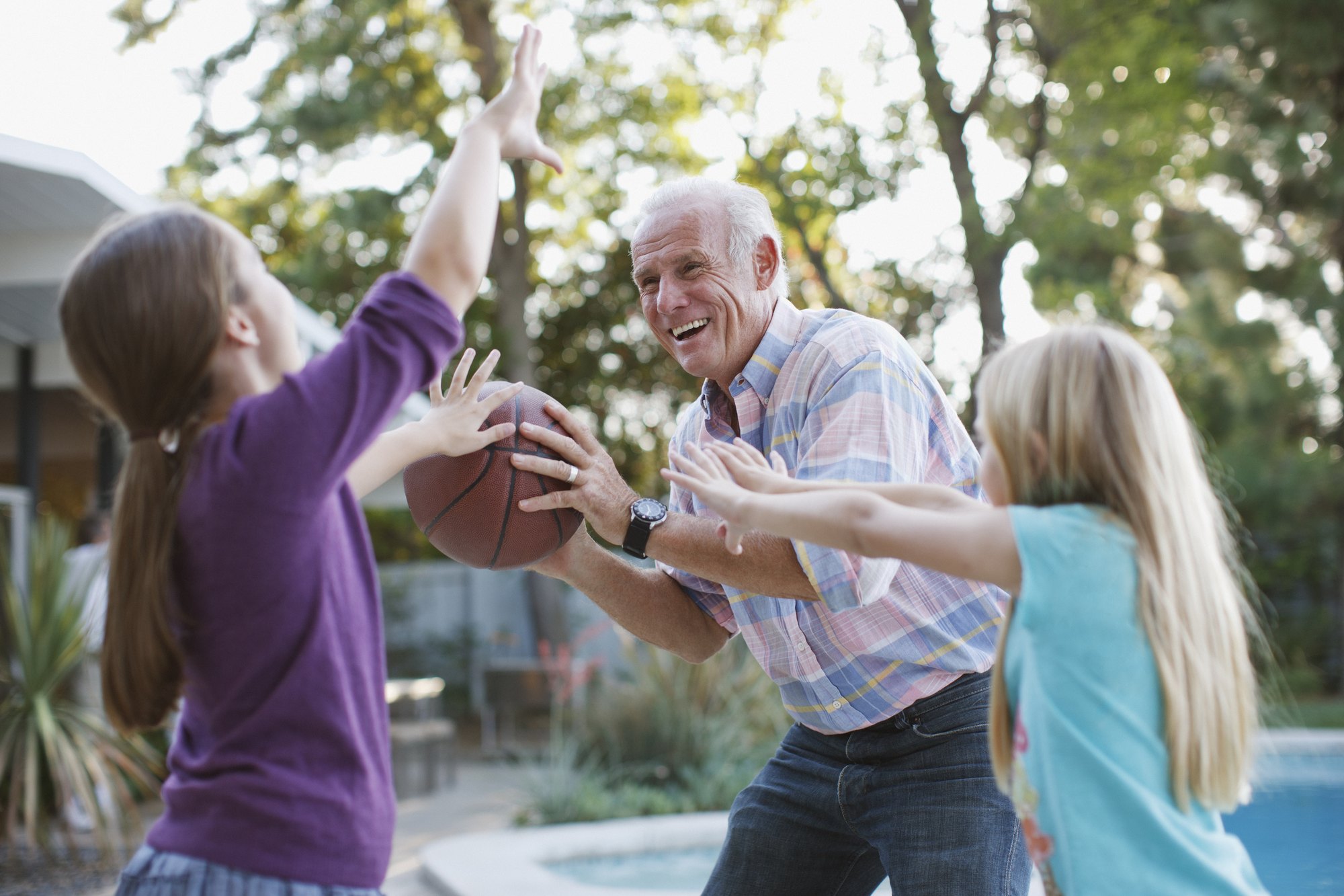 A grandfather laughs as he plays with his grandchildren outdoors