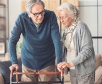 An older couple steady a walker together indoors