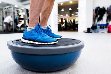Feet in blue sneakers balance on a BOSU trainer
